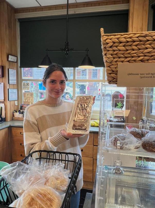 young dark hair woman in a small store holding a tray of sliced bakes bread